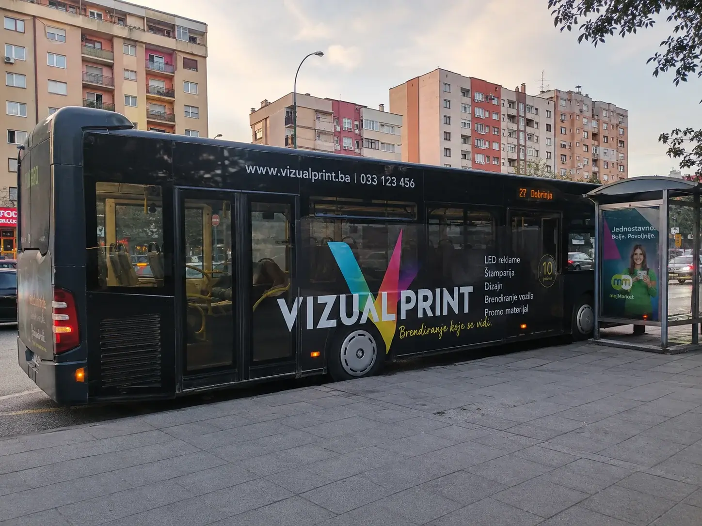 Gradski autobus sa wrap brendingom na autobuskoj stanici